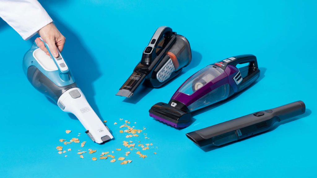 Person using a handheld vacuum to clean crumbs from a kitchen countertop