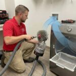 Close-up of vacuum hose reaching inside a dryer vent for improved airflow maintenance