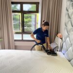 Person vacuuming a mattress to remove dust and allergens for a cleaner sleeping environment